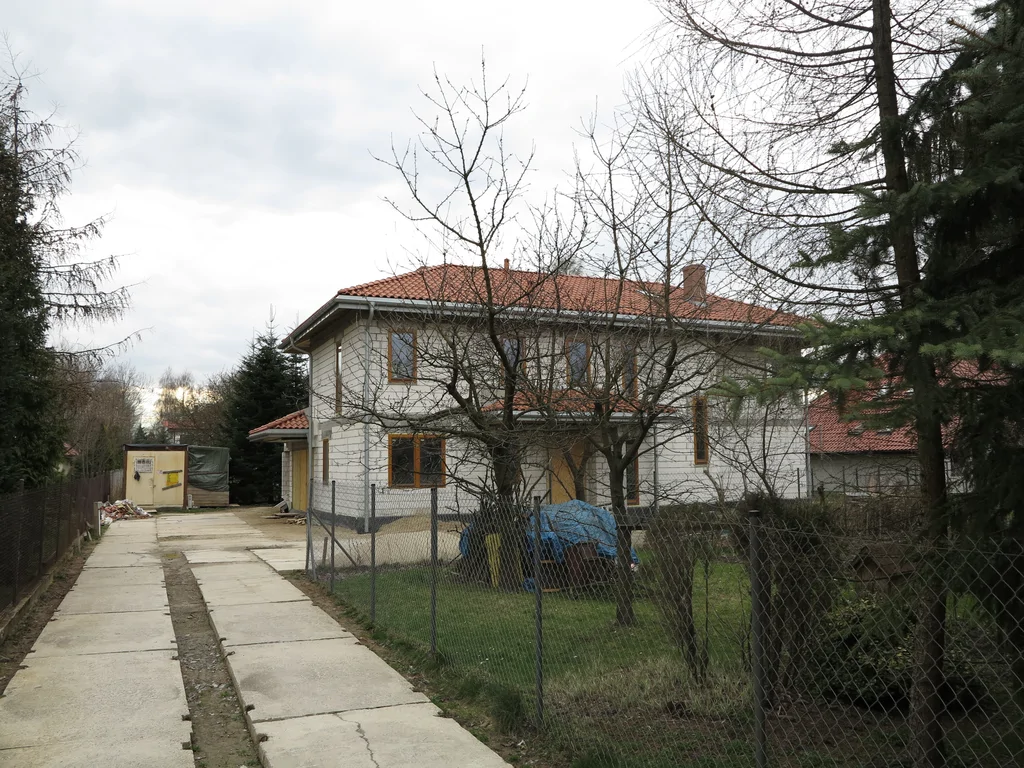 Budowa domu jednorodzinnego, widok z zewnątrz na ciemna stolarka okienna, gotowe pokrycie dachowe