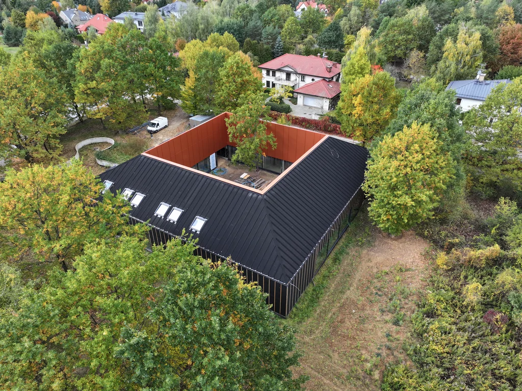 Czarna bryła domu z centralnym patio i drzewem pośrodku