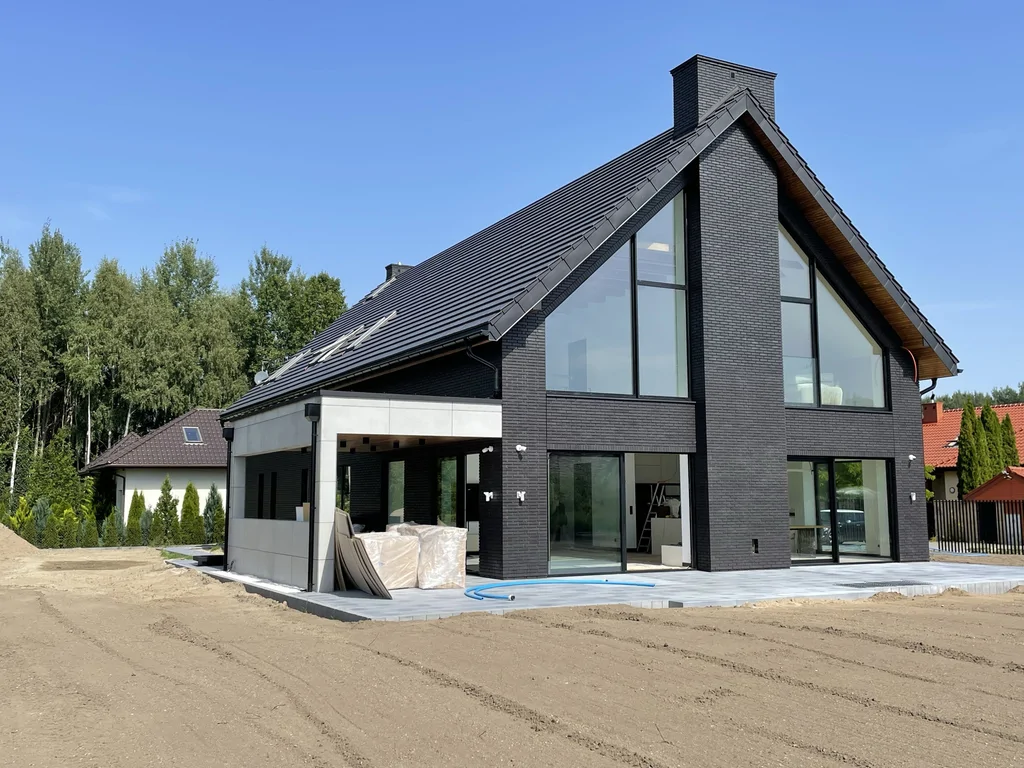 Elewacja szczytowa i taras – duże przeszklenia, komin centralny, bryła domu w Ruścu