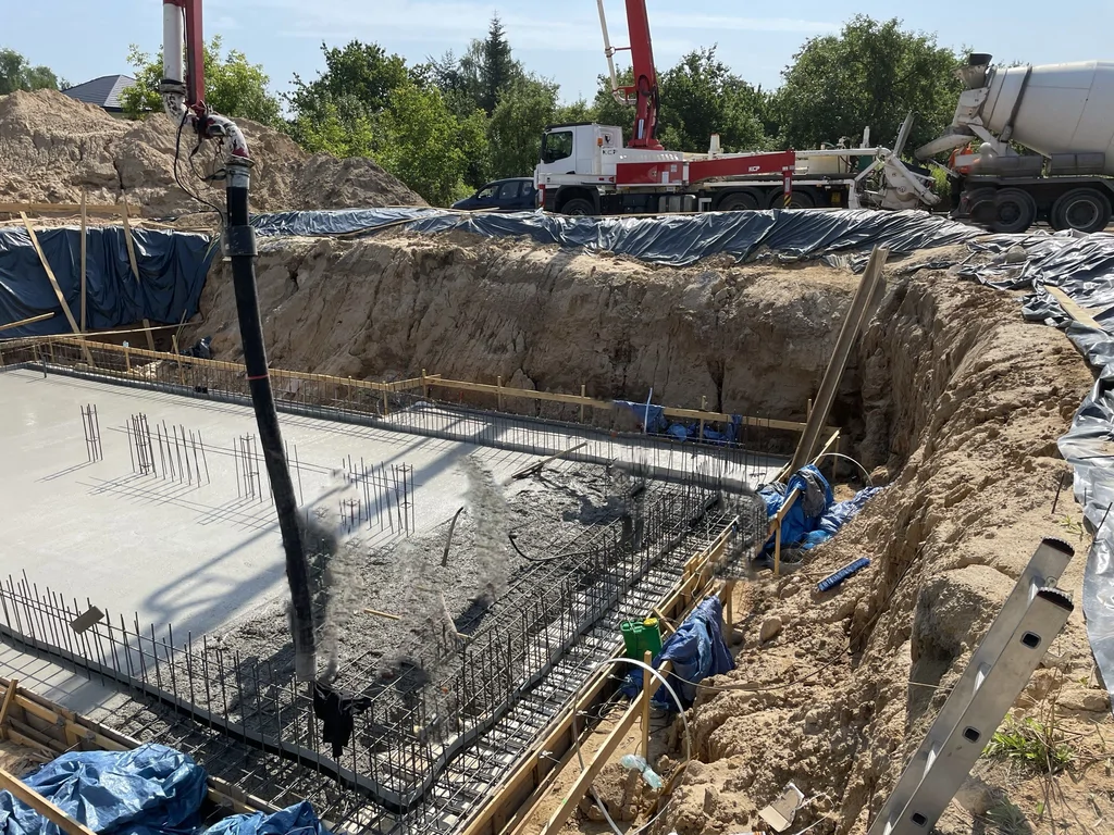 Betonowanie płyty fundamentowej piwnicy z użyciem pompy do betonu podczas realizacji konstrukcji żelbetowej