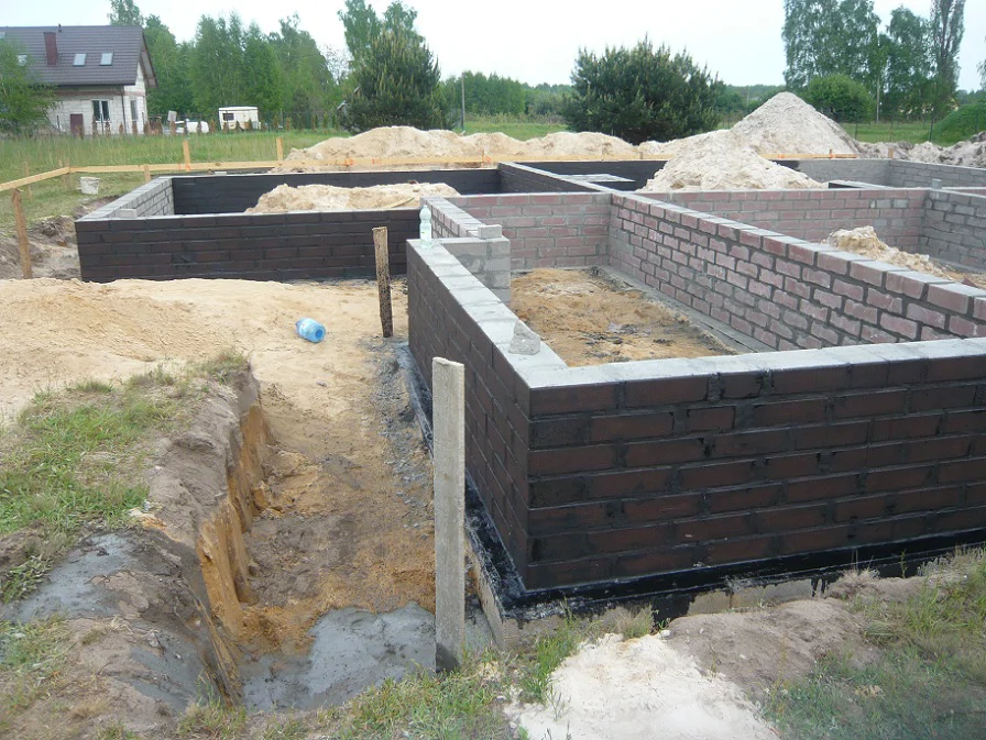 Wymurowane ściany fundamentowe z bloczków, widok na narożnik i izolację fundamentów