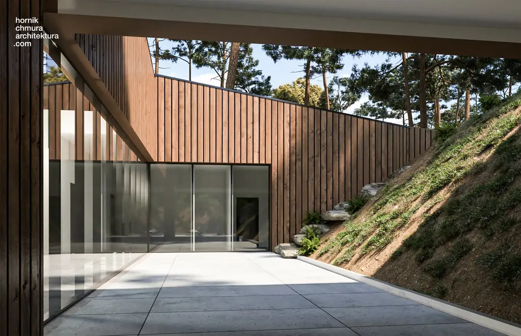 Wizualizacja wewnętrznego patio z dużymi przeszkleniami, drewnianą elewacją i skarpą wykończoną zielenią oraz naturalnym kamieniem.