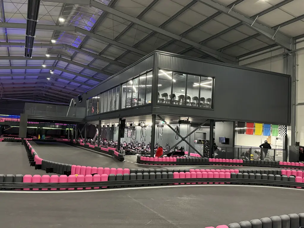 Frontowy widok na gotowy tor gokartowy z zakrętami, strefą flag i antresolą z przeszklonym zapleczem.