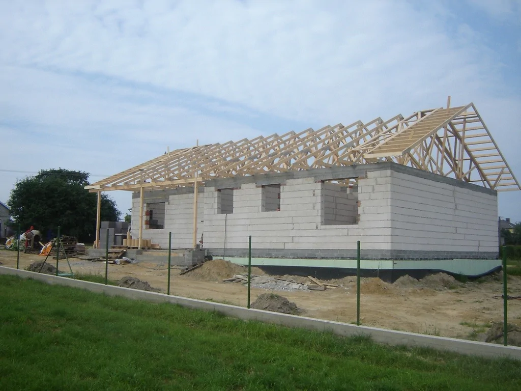 Narożnik domu w stanie surowym z zamontowanymi wiązarami dachowymi