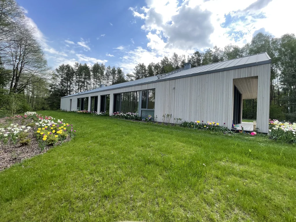 Taras przy domu z widokiem na ogród i drewnianą elewację