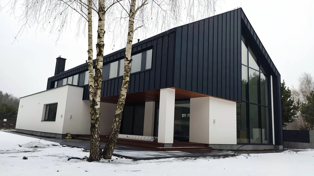 Nowoczesny dom zimą z dużym przeszkleniem szczytowym i tarasem od ogrodu