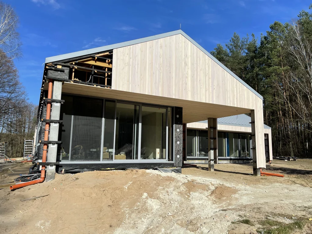 Duże przeszklenia w elewacji i okładzina drewniana – detal strefy dziennej budynku