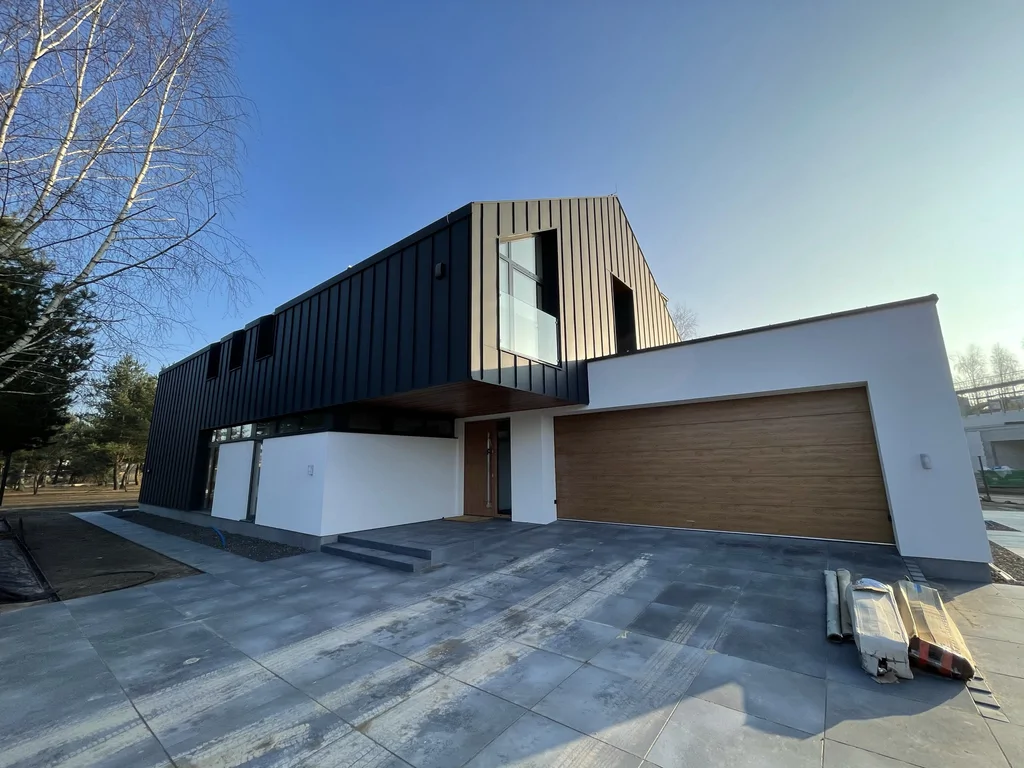 Nowoczesny dom jednorodzinny z garażem dwustanowiskowym, czarna elewacja i duży podjazd