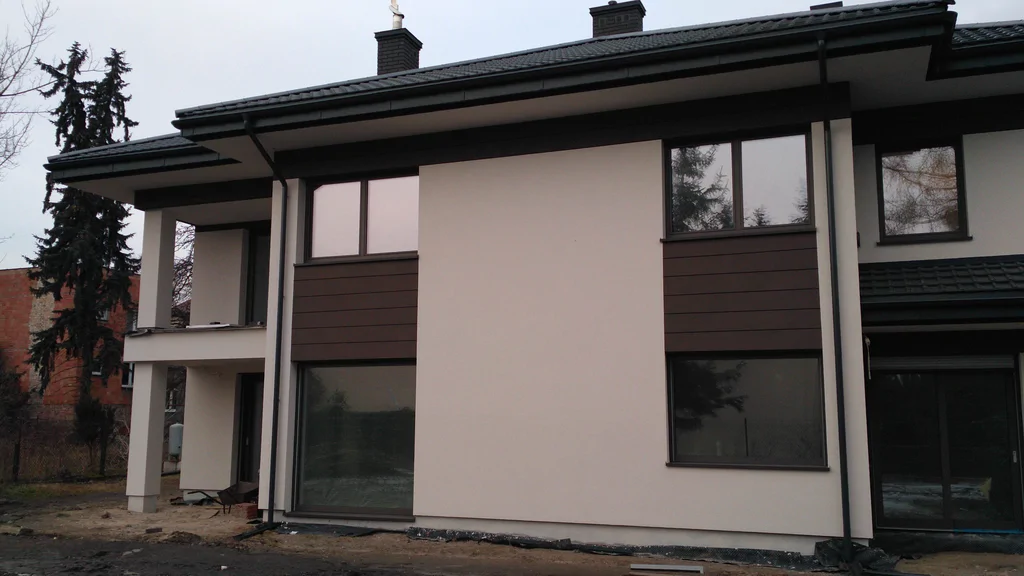 Nowoczesny dom jednorodzinny z jasną elewacją i ciemnym dachem