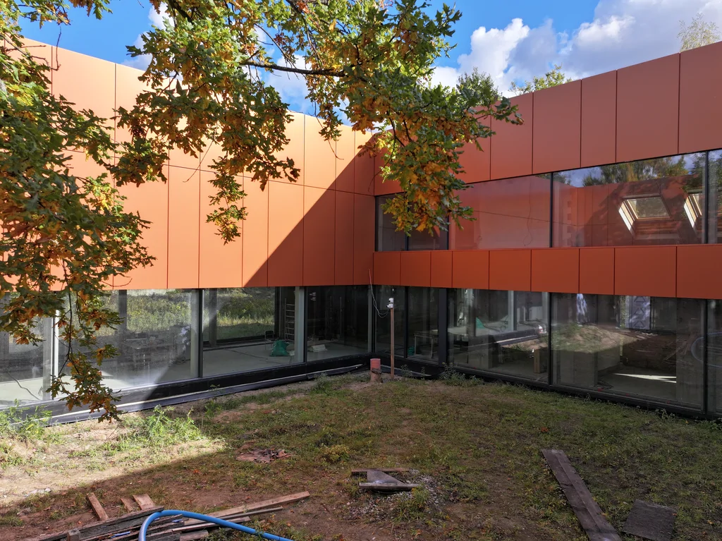 Patio z drzewem i elewacją z płyt elewacyjnych w odcieniu corten