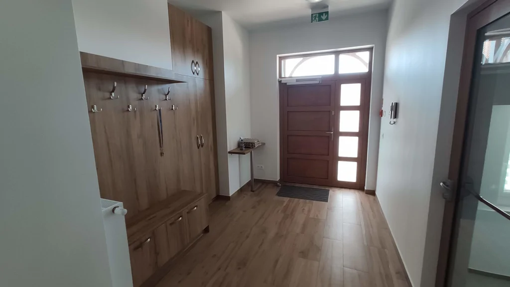 Strefa wejścia, widok na drzwi wyjściowe na ścianie wieszaki i szafka wnękowa