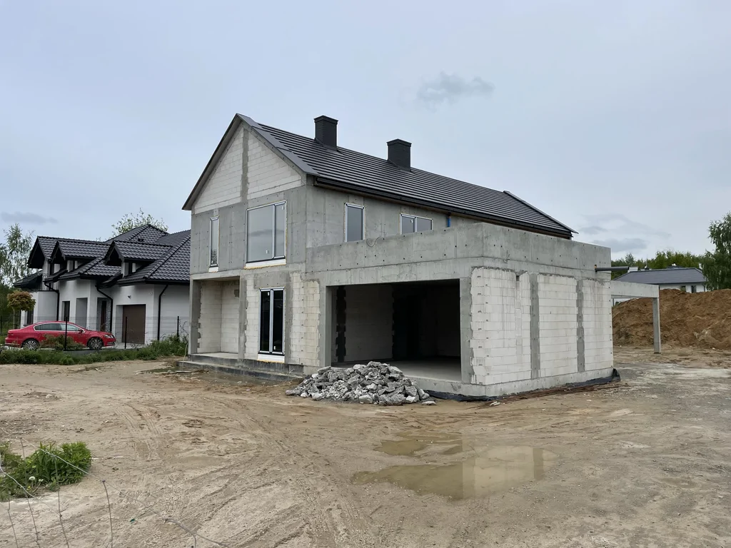 Dom jednorodzinny w stanie surowym z garażem w bryle budynku oraz żelbetową konstrukcją tarasu