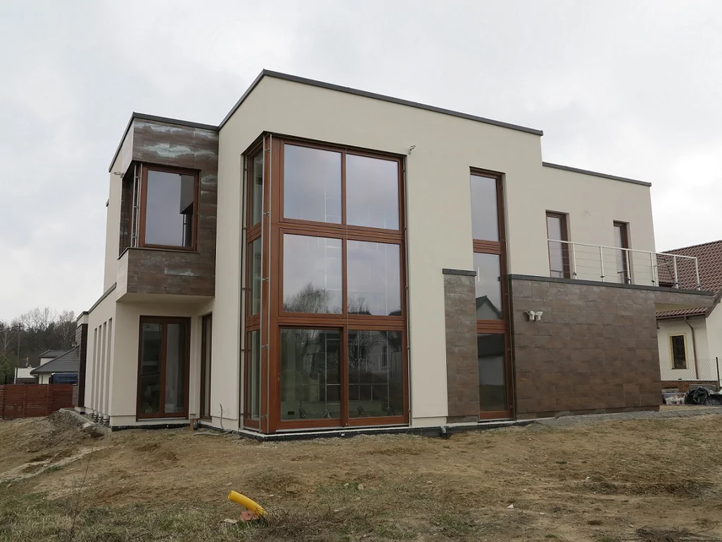 Fasada z wysokim, dwukondygnacyjnym przeszkleniem oraz okładziną w odcieniach brązu