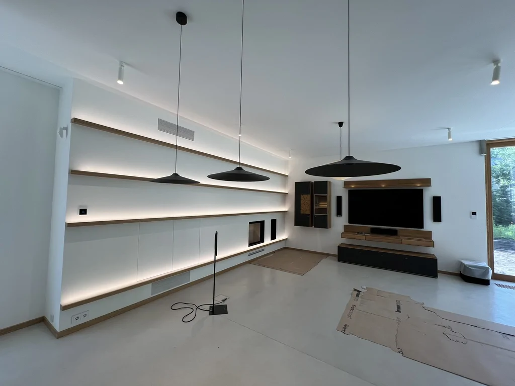 Nowoczesny salon z podświetlanymi półkami, telewizorem i designerskimi lampami wiszącymi