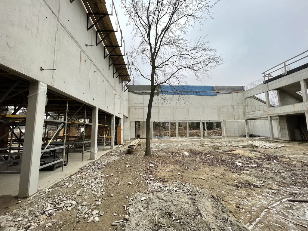 Dziedziniec budynku: ściany z betonu architektonicznego, rusztowania i prace wykończeniowe stanu surowego