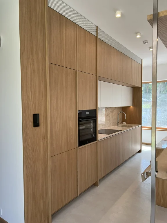 Nowoczesna kuchnia z drewnianą zabudową, piekarnikiem i kamiennym blatem