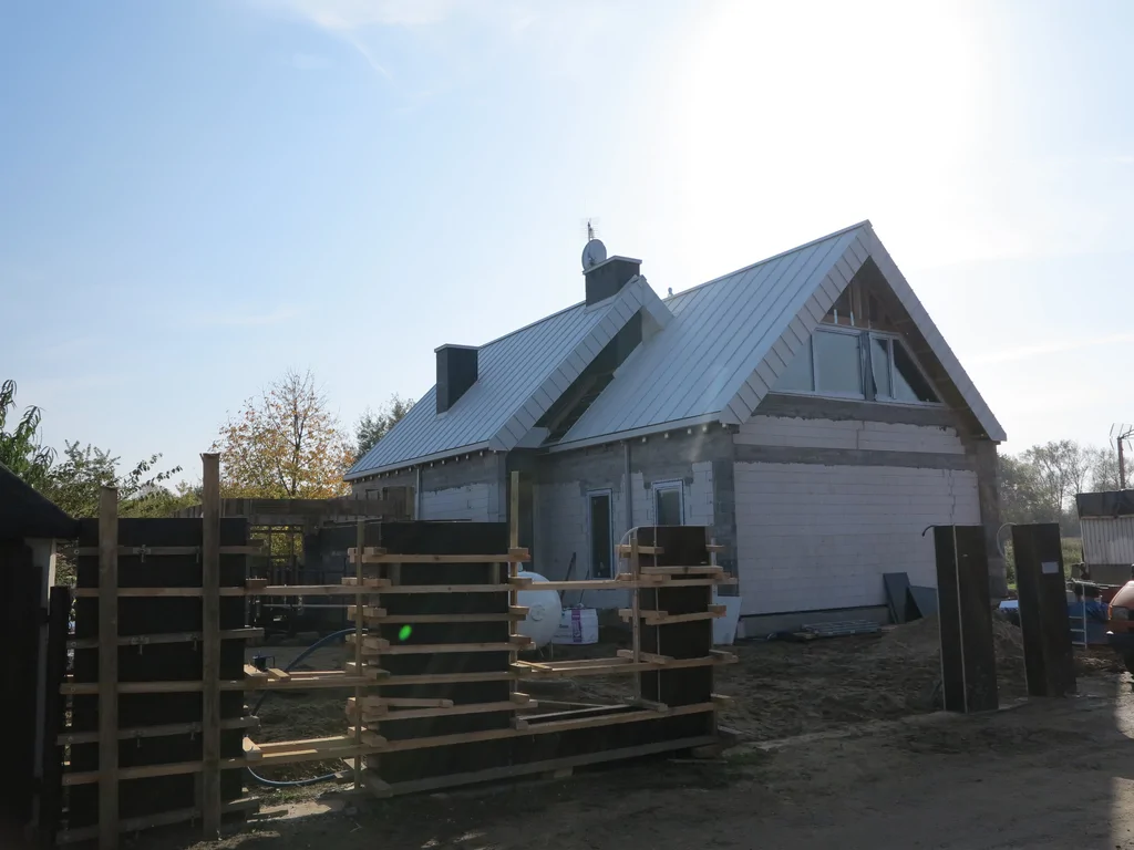 Dom w stanie surowym, dach z blachy, ogrodzenie żelbetowe w szalunku 