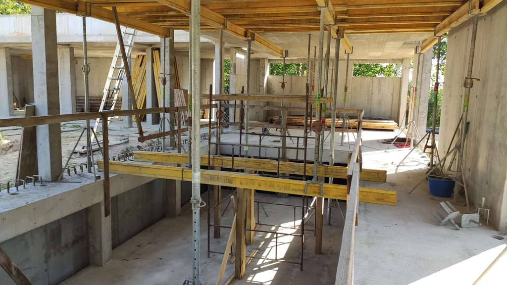 Wnętrze stanu surowego: stropy żelbetowe, podpory i otwory technologiczne przy ścianach z betonu architektonicznego