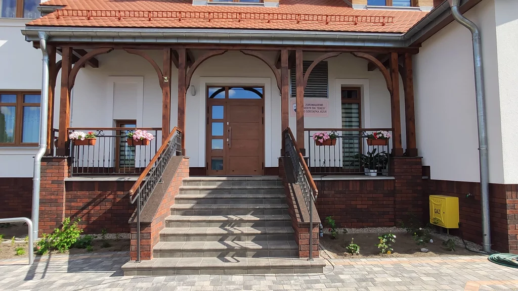 Dom zakonny w Ostródzie od strony wejścia głównego, z podjazdem do piwnicy i wykończeniem terenu wokół budynku