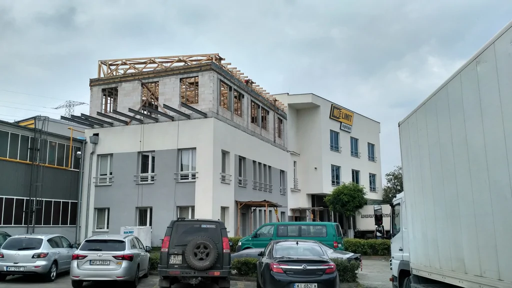 widok z zewnątrz na nadbudowany budynek, ściany z silikatów, wiązary dachowe, wystawione belki na taras 