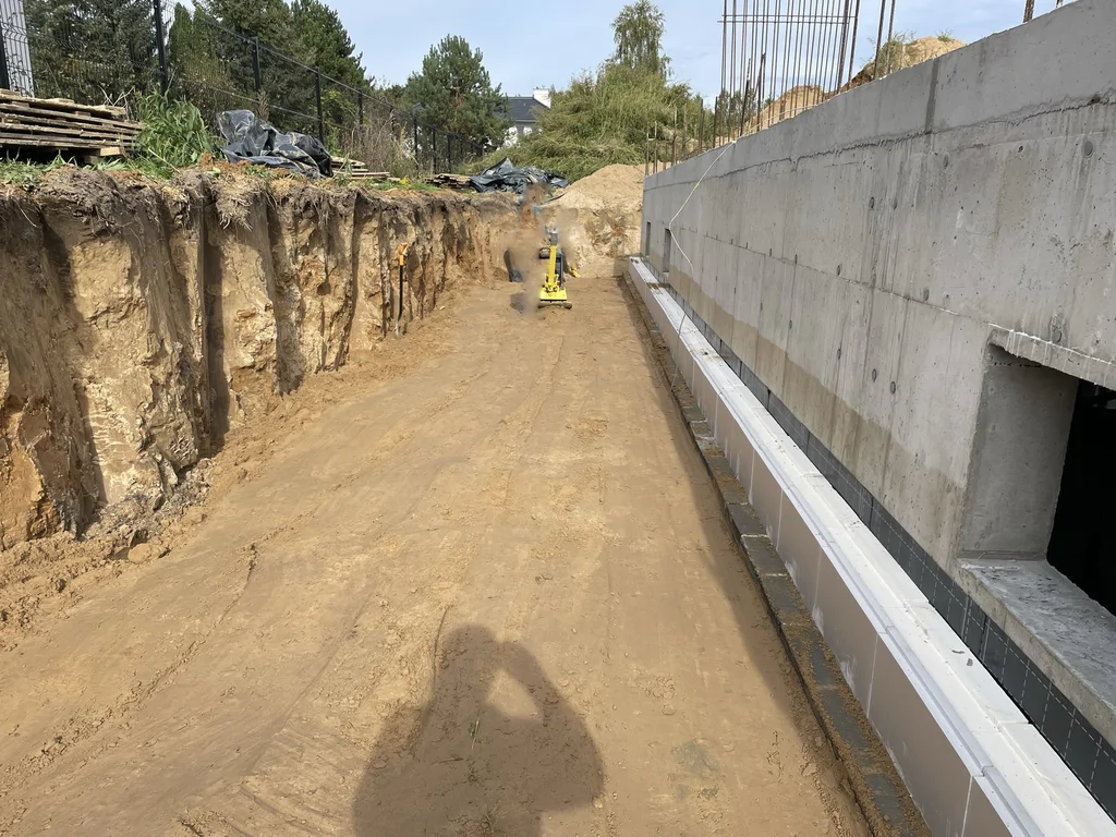 Rampa zjazdowa do garażu podziemnego w trakcie robót ziemnych i przygotowania pod docelową nawierzchnię