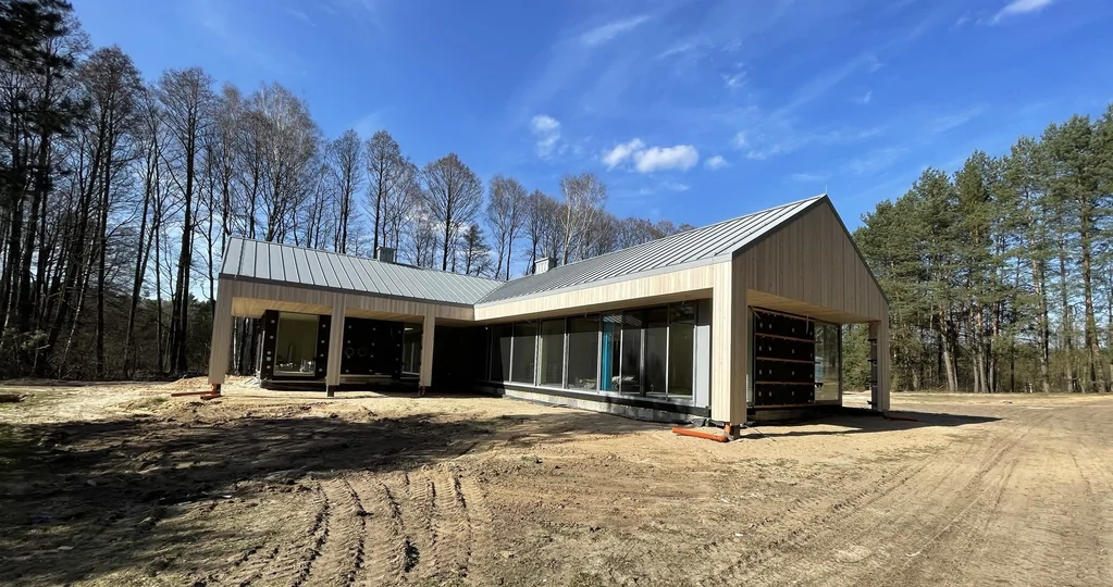 Elewacja z pionowej okładziny drewnianej i duże przeszklenia – widok bryły w trakcie realizacji