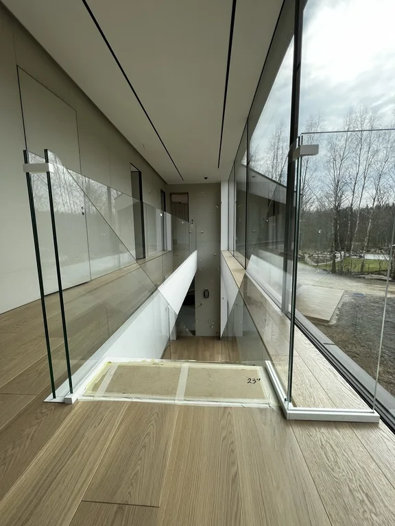 Widok na klatkę schodowa, przeszklona barierka, otwarta przestrzeń dzięki dużym przeszkleniom na stolarce okiennej 