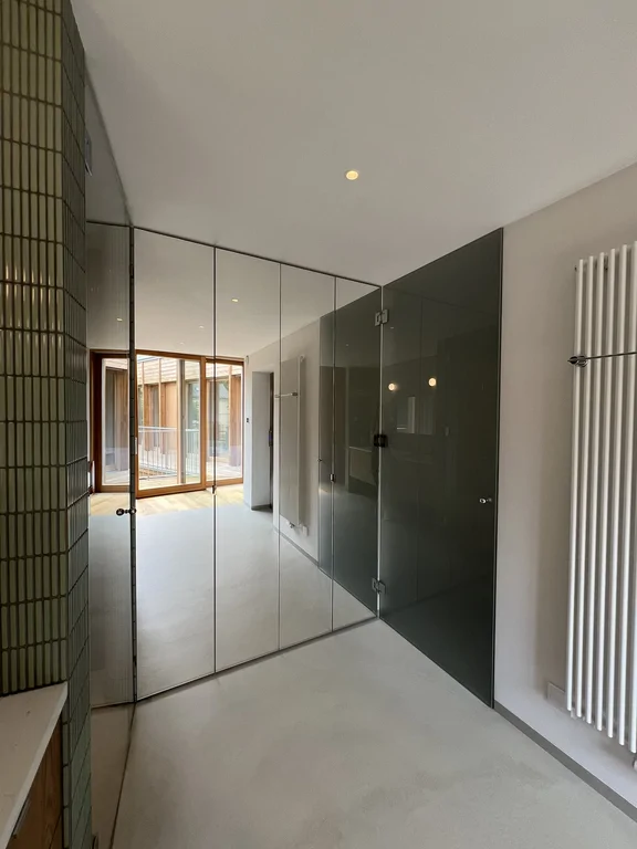 Łazienka z drewnianą zabudową, zielonymi płytkami i wejściem do strefy prysznica