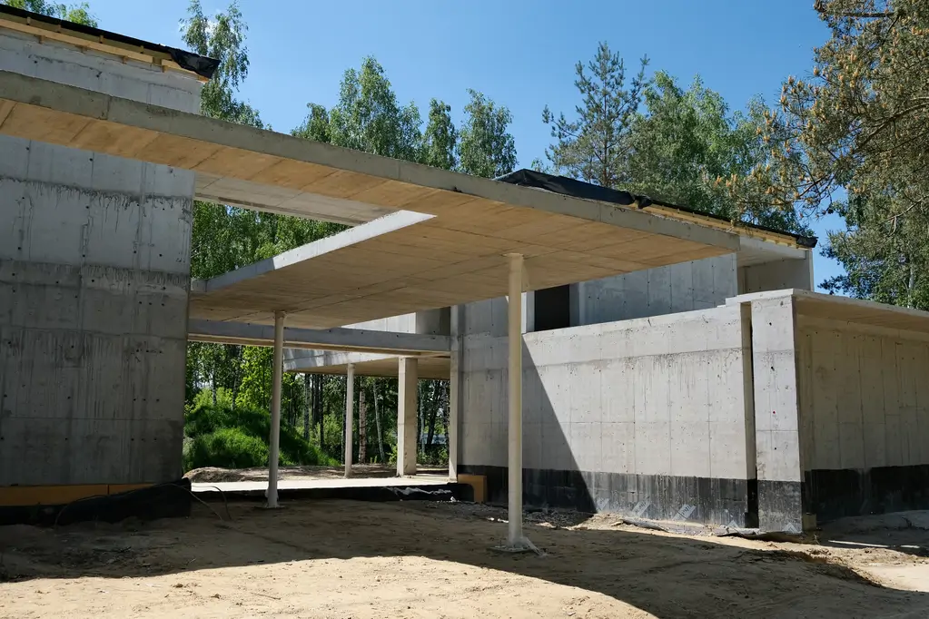 Widok na podcień i część wejściową nowoczesnego domu żelbetowego podczas realizacji stanu surowego.