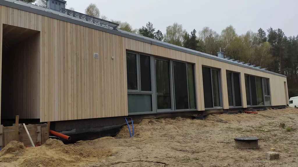 Elewacja boczna z rytmem przeszkleń – okładzina drewniana i dach na rąbek stojący