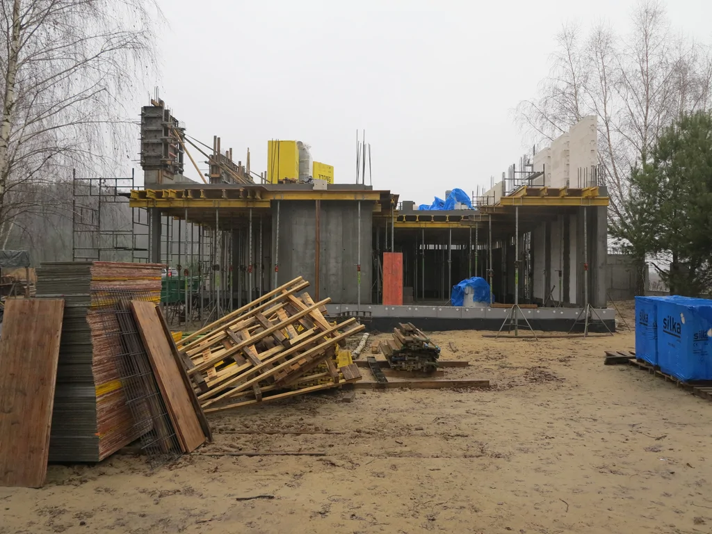 Budowa domu w stanie surowym, ściany z silikatów, w tle szalunki 