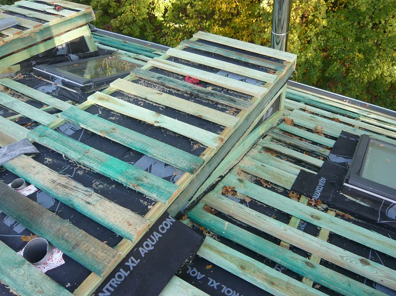 Konstrukcja dachu w trakcie prac: łaty i kontrłaty na membranie, widoczne okna dachowe.