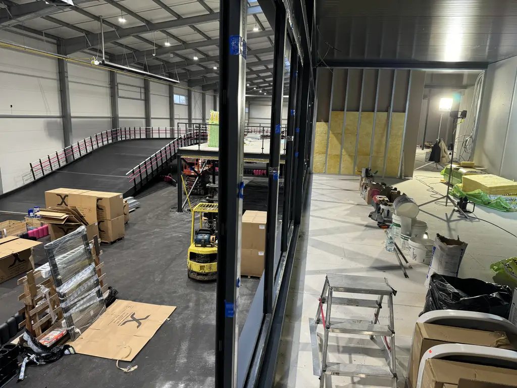 Spiralny najazd antresoli toru gokartowego w trakcie montażu, wykonany z czarnej konstrukcji stalowej z różowymi barierkami.