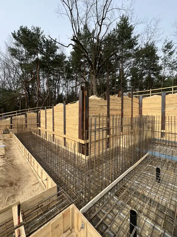 Gęste zbrojenie fundamentów i szalunki przy ścianie oporowej na budowie domu.