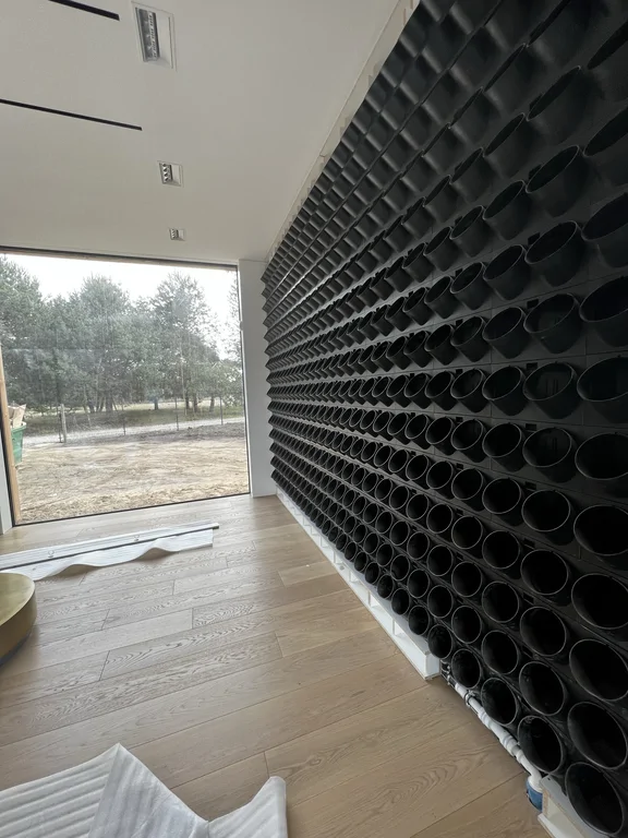 Wnętrze z dużym oknem i dekoracyjną ścianą z modułowych okrągłych wnęk na całej wysokości.