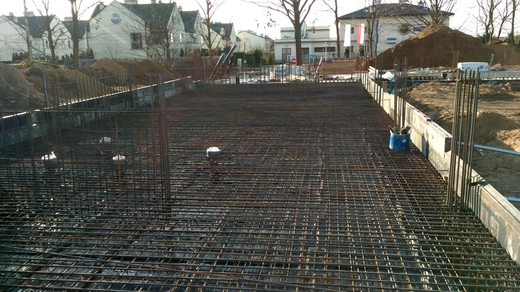 Gęste zbrojenie płyty fundamentowej z wypuszczonymi prętami pod ściany – przygotowanie do zalania żelbetu