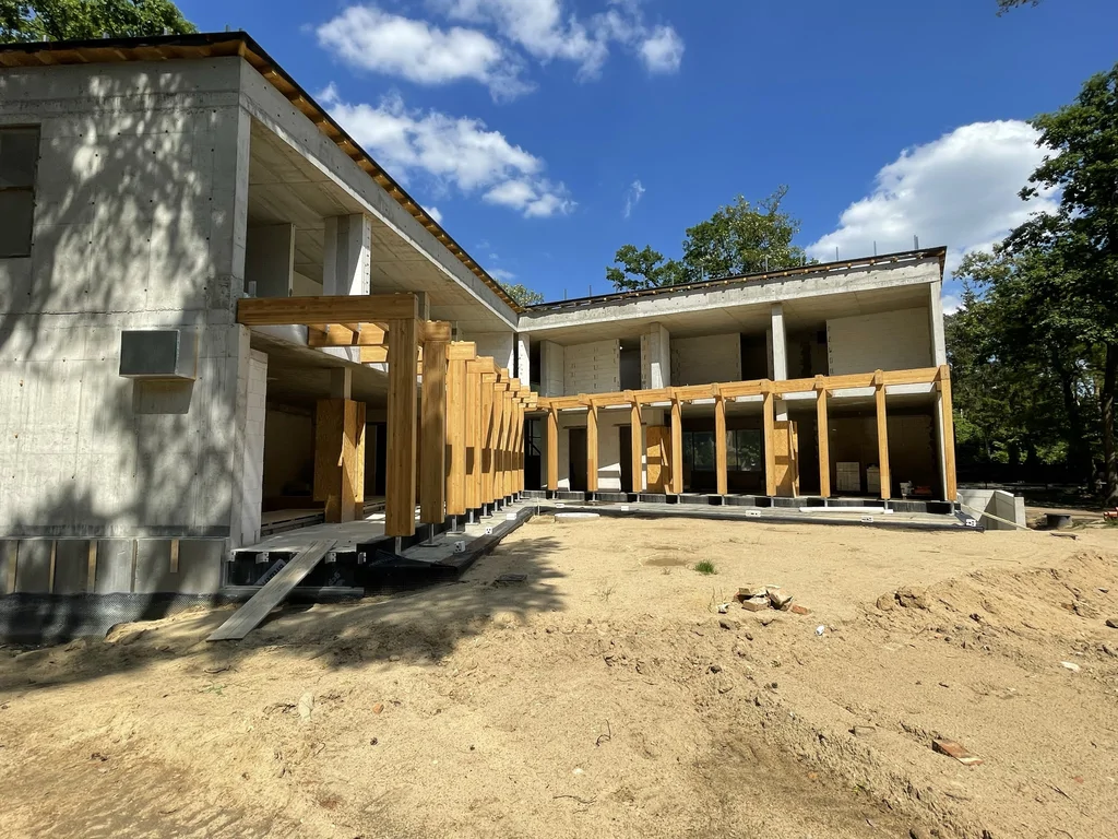 Perspektywiczny widok elewacji ogrodowej domu jednorodzinnego z drewnianą pergolą i żelbetową konstrukcją