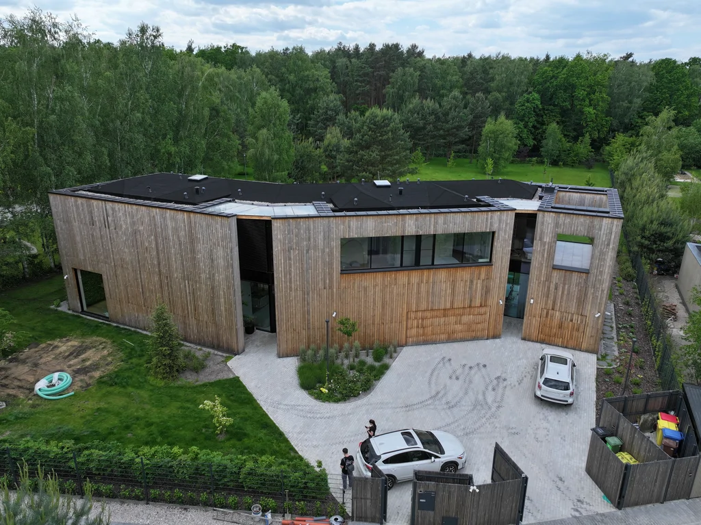 Dom Prawdziwka – ujęcie z drona od strony podjazdu i garażu, drewniana elewacja i płaski dach.