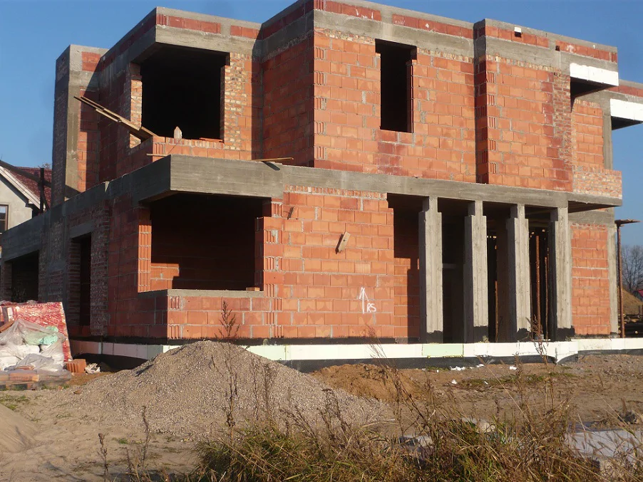 Narożnik budynku w stanie surowym – otwory okienne bez stolarki i widoczny żelbet