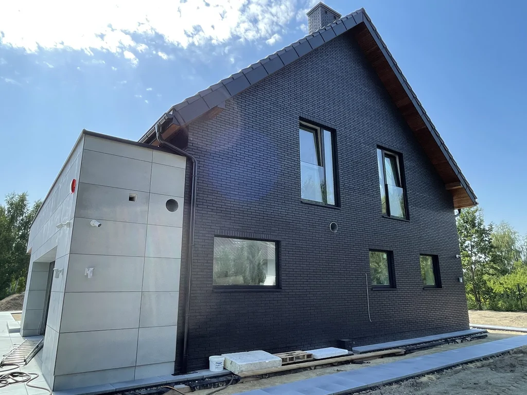 Elewacja tylna/narożna – czarna cegła i jasna bryła garażu, dach dwuspadowy