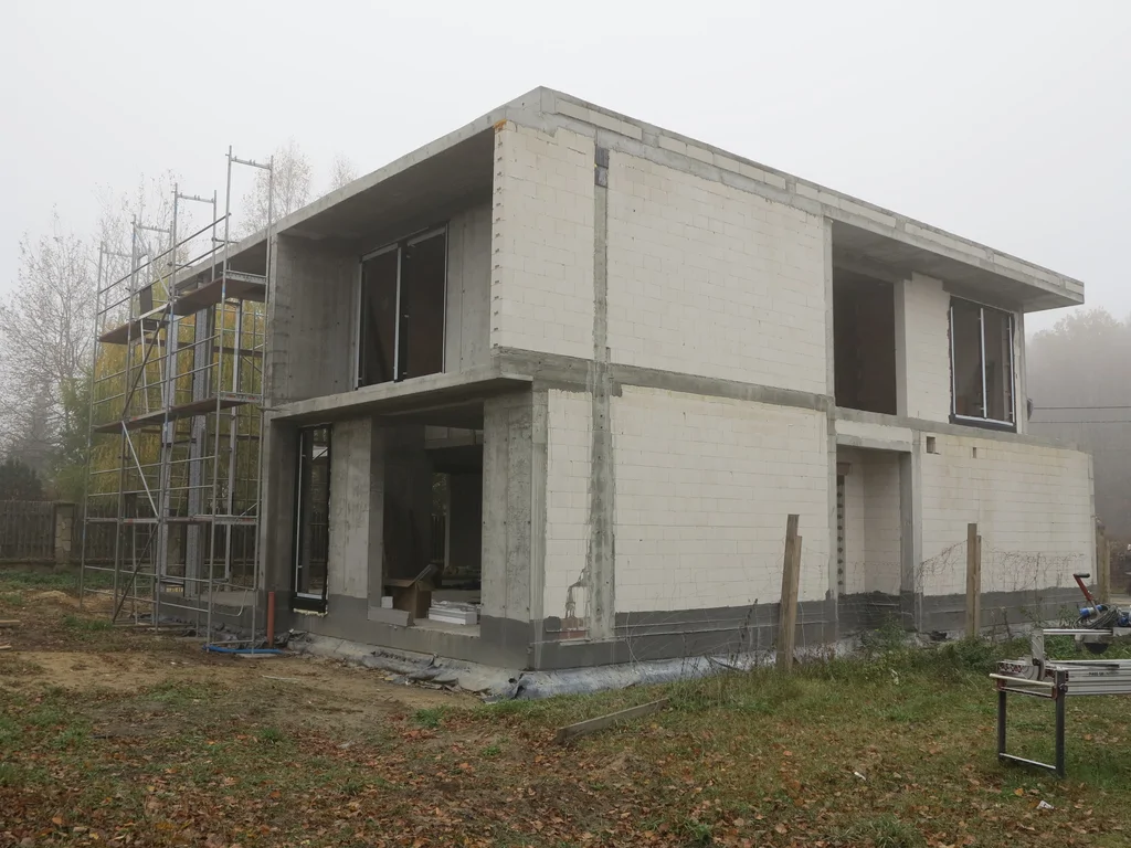 Stan surowy budynku, ściany pustak ceramiczny w tle rusztowania 