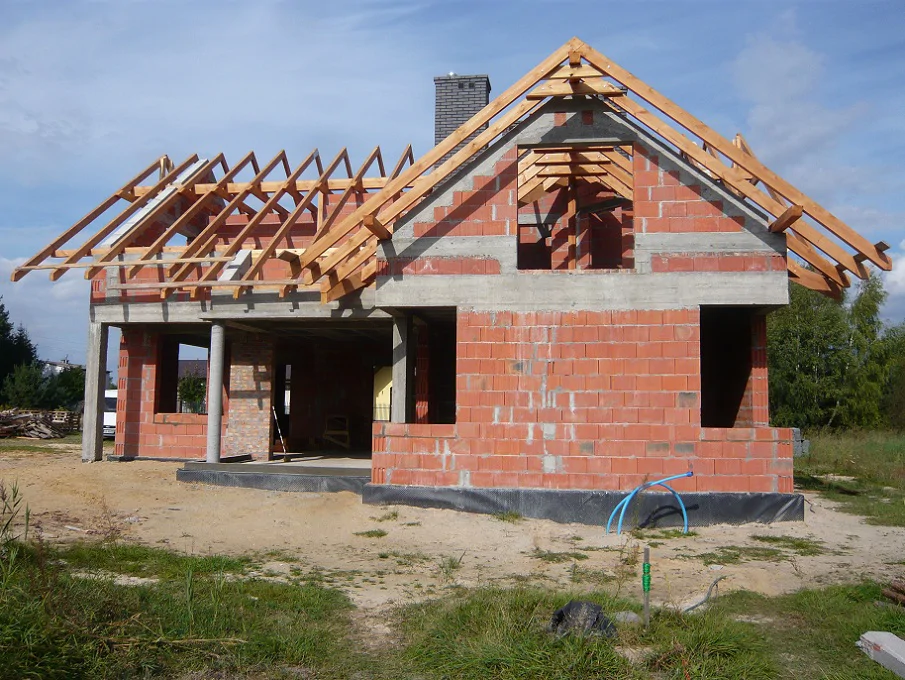 Front budynku z konstrukcją dachu w stanie surowym