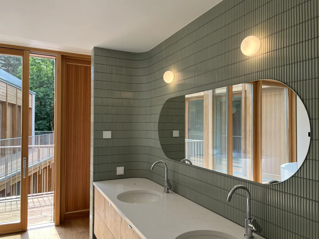 Łazienka z podwójną umywalką, zielonymi płytkami i wyjściem na balkon