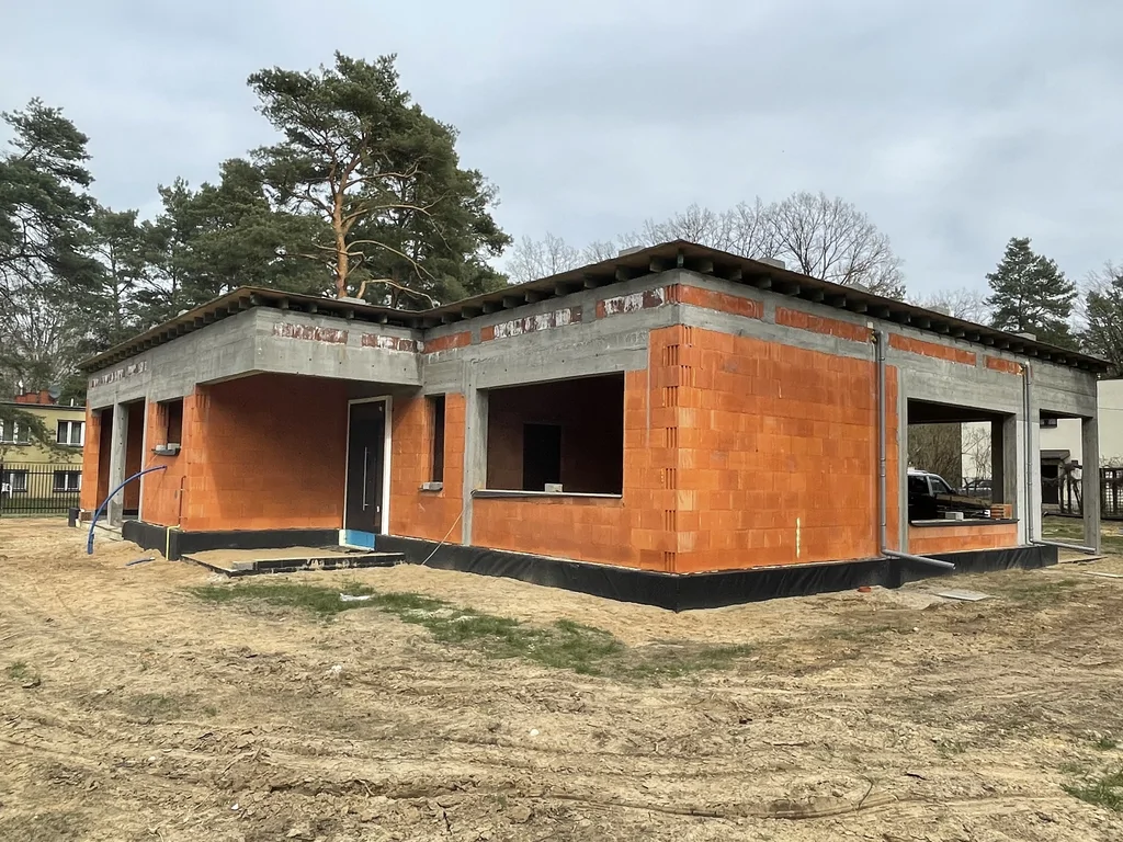 Narożny widok domu w stanie surowym z żelbetową konstrukcją i dużymi przeszkleniami