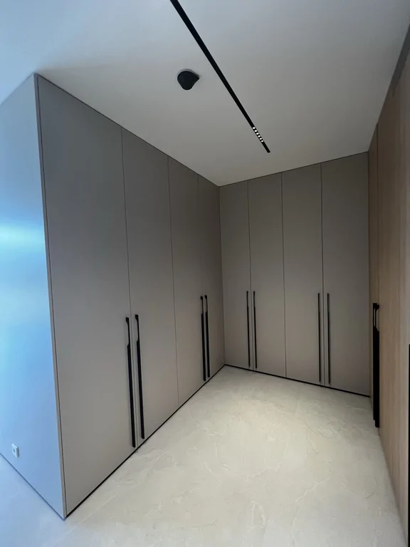 Pełna zabudowa w macie, z uchwytami w czerni i jasną posadzką. Maksymalizacja pojemności bez wizualnego chaosu.